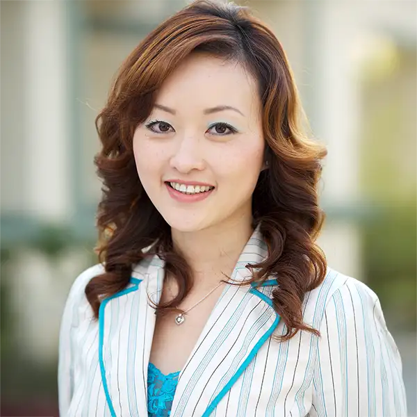 Professional headshot of a smiling Asian woman in a striped blazer.