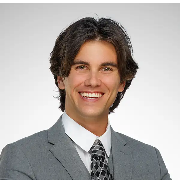 Professional headshot of a smiling man in a grey suit